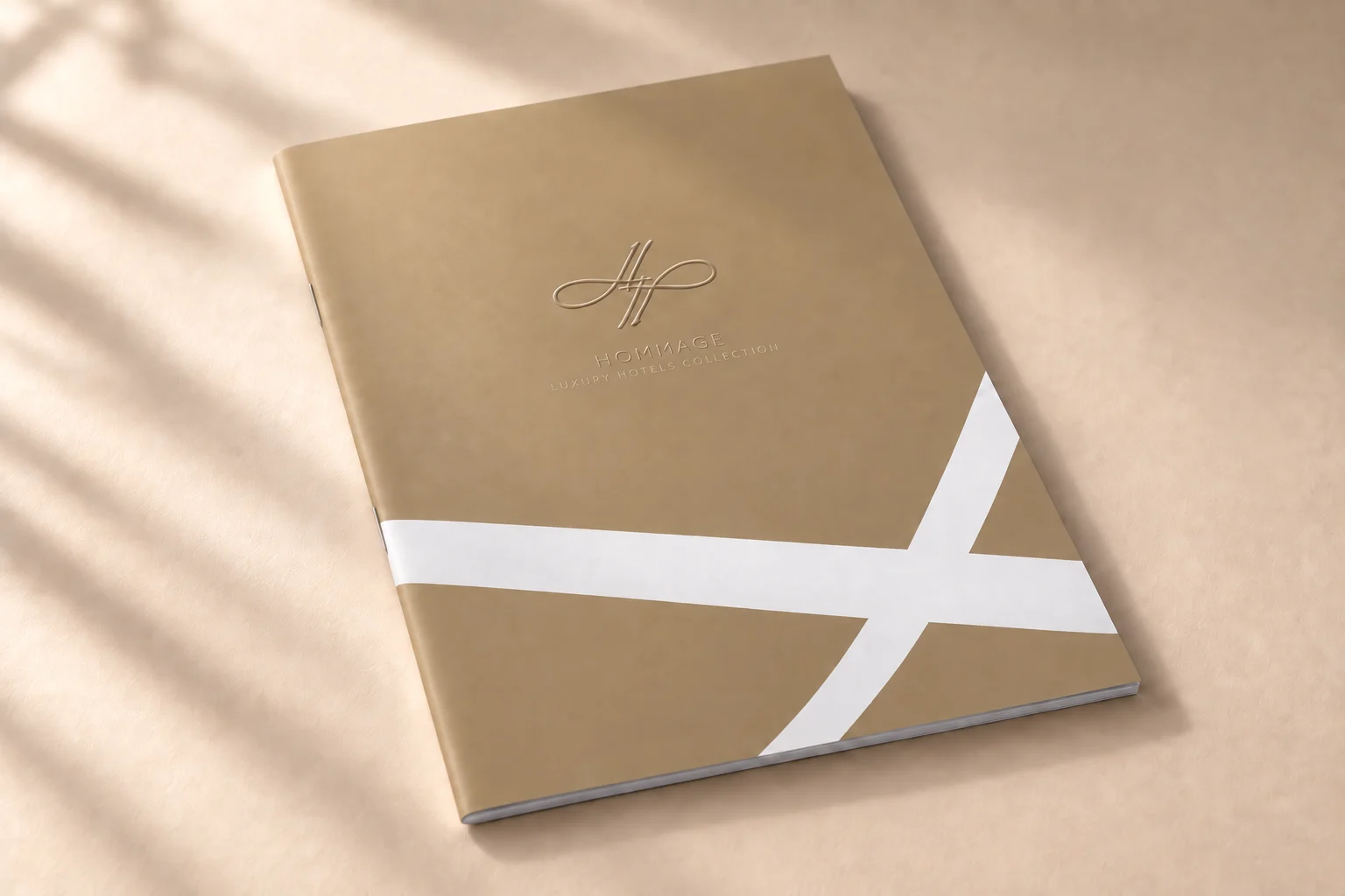 Goldfarbenes Cover mit weißem grafischem Band – Hochzeitsbroschüre Hommage Hotels, Gestaltung Inga Sineux für Justfrank